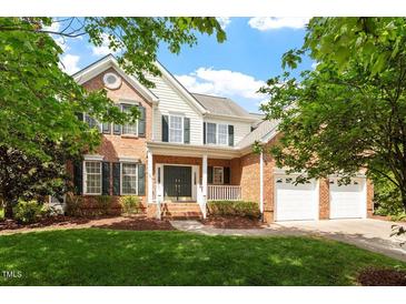 Charming brick and siding two-story home with lush green lawn, mature trees, and a welcoming front porch at 9117 Meadow Mist Ct, Raleigh, NC 27617