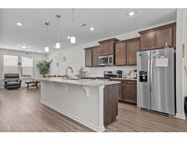 Spacious kitchen features a large island, granite countertops, stainless steel appliances, and wood-look flooring at 987 Parkstone Towne Blvd, Knightdale, NC 27545