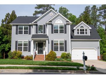Charming two-story home boasts gray siding, black shutters, lush landscaping, and attached two-car garage at 101 Worsham Dr, Chapel Hill, NC 27516