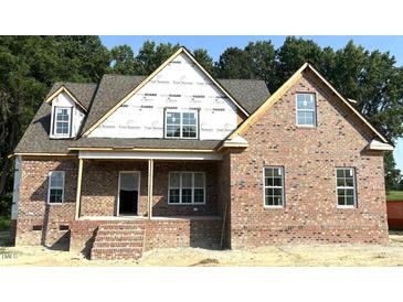 New brick home with white trim windows and a covered porch, set against a backdrop of mature trees at 1589 S Old Carriage Rd, Rocky Mount, NC 27804