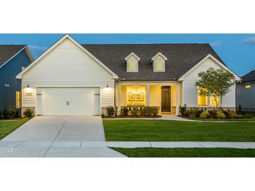 Charming one-story home boasting a pristine lawn, covered porch and attached two-car garage at 1605 Garden Park Cir, Fuquay Varina, NC 27526