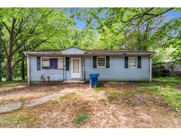 Charming single-story home with light blue siding and traditional shutters, nestled amongst mature trees at 2733 Thelma St, Durham, NC 27704