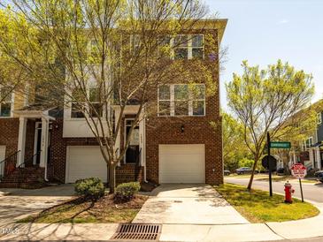 Brick townhome featuring an attached garage and well-maintained landscaping at 3000 Summerhouse Rd, Cary, NC 27519