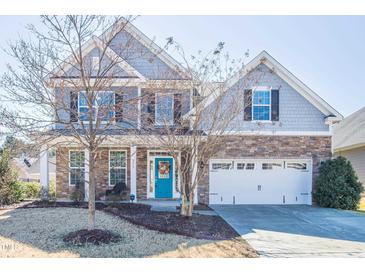Charming two-story home featuring stone accents, light-blue siding and a vibrant, eye-catching blue front door at 311 Windrush Ln, Durham, NC 27703