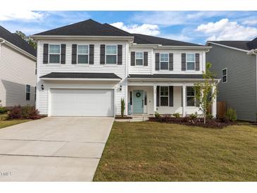 Charming two-story home with a well-manicured lawn and a two-car garage at 323 Oak Branch Trl, Garner, NC 27529