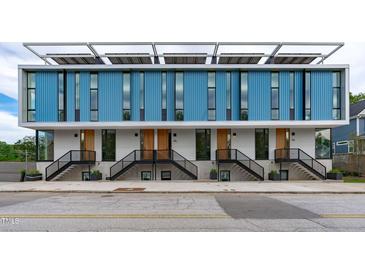 Modern townhome exterior featuring blue siding, large windows, and staircase entryways at 501 S Bloodworth St # 104, Raleigh, NC 27601
