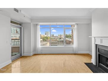 Bright living room features large windows offering city views, a fireplace, and hardwood floors at 510 Glenwood Ave # 510, Raleigh, NC 27603