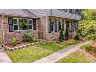 Charming brick home featuring black shutters, well-maintained landscaping, and a welcoming front porch at 5632 Falkirk Dr, Durham, NC 27712
