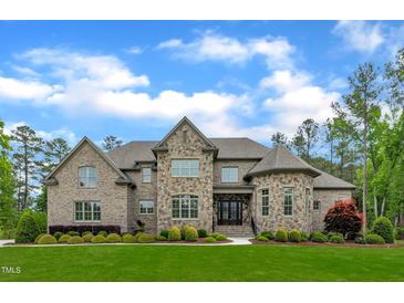 Beautiful two-story stone and brick home with a manicured lawn and inviting double door entrance at 628 Carolina Crossings Dr, Apex, NC 27523