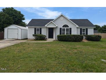 Charming single-story home with a well-manicured lawn, black shutters, and a detached garage at 111 Shadow Bend Ln, Selma, NC 27576