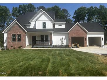 New construction home with white siding, red brick accents, black roof, and an attached two-car garage at 123-125 Ottawa Dr., Louisburg, NC 27549
