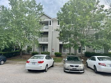 Multi-level condo building featuring multiple balconies with gray siding and mature trees at 1321 Crab Orchard Drive # 203, Raleigh, NC 27606