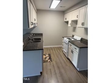 Galley kitchen with granite countertops and white cabinets and neutral colored flooring at 3049 Huntleigh Dr, Raleigh, NC 27604