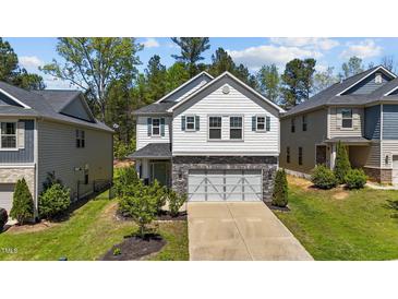 Charming two-story home featuring a two-car garage, stone accents, and a well-maintained front yard at 4009 Reunion Creek Pkwy, Apex, NC 27539