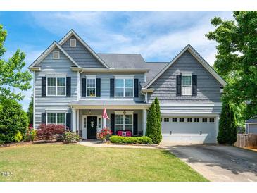 Charming two-story home with beautiful landscaping, complemented by an inviting front porch and well-maintained lawn at 6901 Rex Rd, Holly Springs, NC 27540