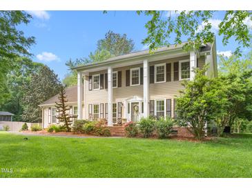 Inviting two-story home showcasing a well-manicured lawn, charming landscaping, and a classic colonial design at 1207 Candlewood Dr, Elon, NC 27244