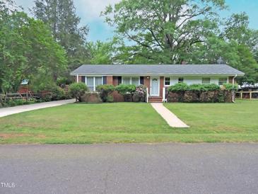 Charming single-story home featuring a well-maintained lawn, brick accents, and a welcoming front entrance at 122 E Orange St, Hillsborough, NC 27278