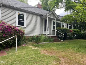 Charming home featuring a covered entryway, traditional siding, and lush landscaping with flowering shrubs at 1812 House Ave, Durham, NC 27707