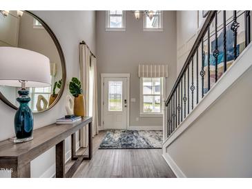 Bright foyer features a staircase, wood floors, a stylish mirror, and a console table with decor at 3004 Dog Rose Dr # 309, Durham, NC 27703