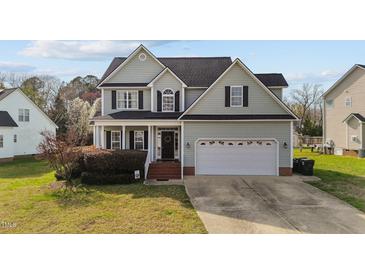 Charming two-story home with a well-manicured lawn and attached two car garage at 323 Windgate Dr, Clayton, NC 27527