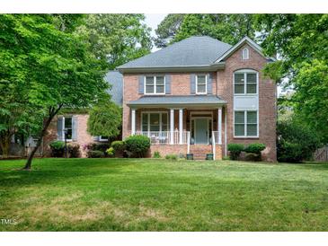 Charming two-story brick home with a covered porch and lush front lawn surrounded by mature trees at 5112 Wolcott Ct, Fuquay Varina, NC 27526