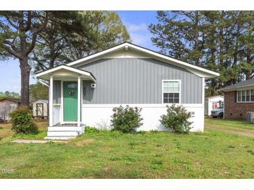 Charming single story home with grey siding, a white brick foundation, and a bright green front door at 607 E Granville St, Dunn, NC 28334