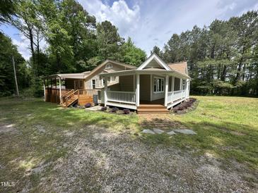 Charming cottage-style home with a covered porch and lush landscaping at 10017 Oakley Rd, Zebulon, NC 27597
