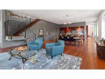 Open-concept living room featuring hardwood floors, exposed brick, and modern staircase design at 101 Morris St # D, Durham, NC 27701