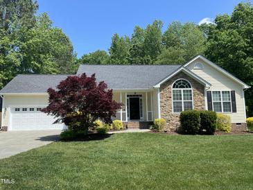 Charming single-story home featuring a stone accent wall, well-manicured lawn, and mature trees on a sunny day at 115 Oak Leaf Trl, Youngsville, NC 27596