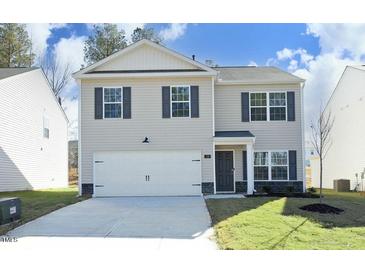 Charming two-story home featuring a two-car garage, classic shutters, and a well-manicured lawn at 139 Palm Drive Dr, Sanford, NC 27332
