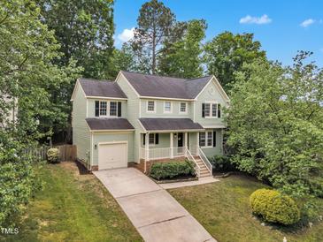 Charming two-story home with landscaped yard and inviting front porch, set against a backdrop of lush greenery at 221 Mint Hill Dr, Cary, NC 27519