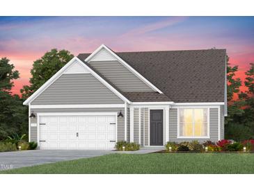 Charming single-story home featuring gray siding, a two-car garage, and a beautifully landscaped front yard at sunset at 2429 Forsythia Trl, Fuquay Varina, NC 27526