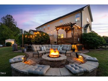 Inviting backyard with a stone fire pit, seating area, and pergola-covered deck, perfect for outdoor gatherings at 48 Falling Oak Ct, Clayton, NC 27520