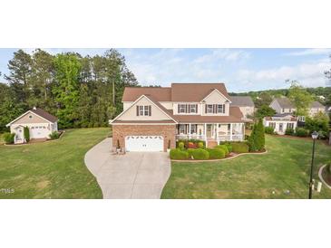 Charming two-story home boasts a manicured lawn, a brick-accented garage, and a welcoming front porch at 48 Falling Oak Ct, Clayton, NC 27520