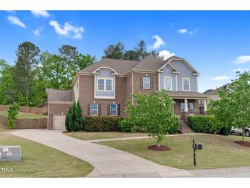 Charming two-story brick home with blue accents, lush landscaping, and a welcoming front yard at 5004 Clowser Minnow Ct, Wake Forest, NC 27587