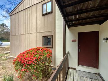 Charming home exterior with a cozy entryway, red door, and blooming azalea bush at 5078 Flint Ridge Pl, Raleigh, NC 27609
