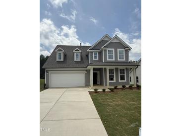 Charming two-story home with gray siding, dormer windows, and a covered front porch at 567 Winding Creek Dr, Lillington, NC 27546