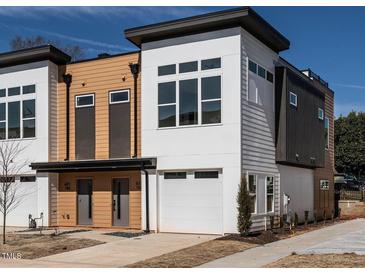 Modern townhome features sleek white and wood paneling with large windows and an attached garage at 611 Walnut Hts Dr # 101, Raleigh, NC 27610