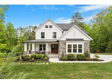 Beautiful two-story home with stone accents, a charming front porch, and lush landscaping at 66 Romie Ct, Pittsboro, NC 27312