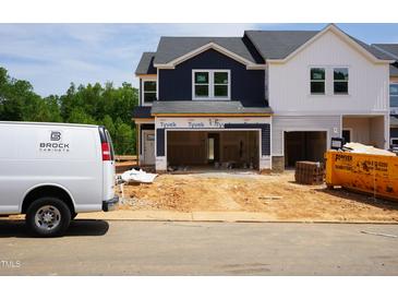 New construction townhome exterior showcasing the garage and uninstalled features under a cloudy sky at 1041 Winding Spring Dr, Mebane, NC 27302