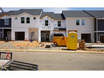 Image shows the exterior of homes under construction with Tyvek wrap, dumpsters, and a portable restroom at 1049 Winding Spring Dr, Mebane, NC 27302