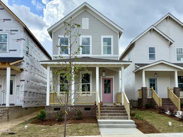 Charming two-story home with a welcoming front porch and a delightful pink front door at 127 Mossy Falls Way, Wendell, NC 27591