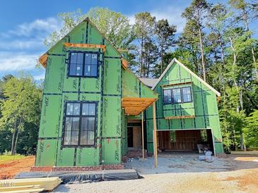 New home in construction phase, showcasing framing, black windows, and green weather resistant barrier at 3324 Founding Place, Raleigh, NC 27612