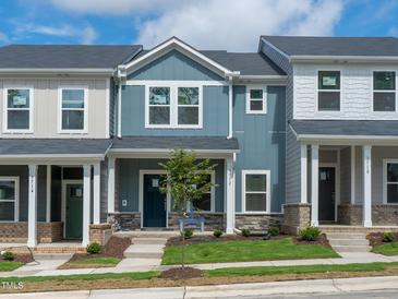 Charming new townhome with blue siding, stone accents, landscaped yard, and inviting front entrance at 3712 Rosebush Dr, Zebulon, NC 27597