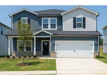 Charming two-story home with a well-manicured lawn, two-car garage, and a mix of horizontal and shake siding at 659 White Birch Ln, Angier, NC 27501