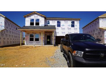 New construction featuring Tyvek wrap, situated on a lot with fresh gravel and a black truck parked nearby at 677 White Birch Ln, Angier, NC 27501