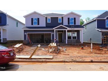 New construction home with a two-car garage in a suburban neighborhood, with worker on site at 725 Deschutes Dr, Garner, NC 27529