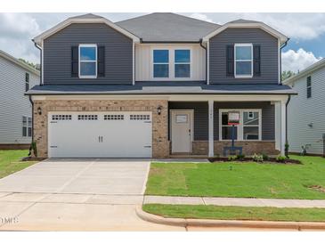 Two-story home with a two car garage, gray siding, brick facade, and well manicured front yard at 741 Deschutes Dr, Garner, NC 27529