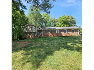 Charming brick home with green shutters and a well-maintained lawn on a sunny day at 1102 Parkwood Dr, Siler City, NC 27344