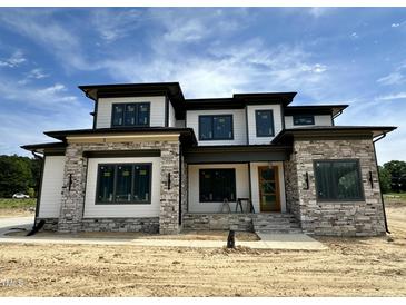Stunning new home featuring stone and white siding, complemented by dark trim and a welcoming entryway at 200 Broadleaf Ln, Louisburg, NC 27549